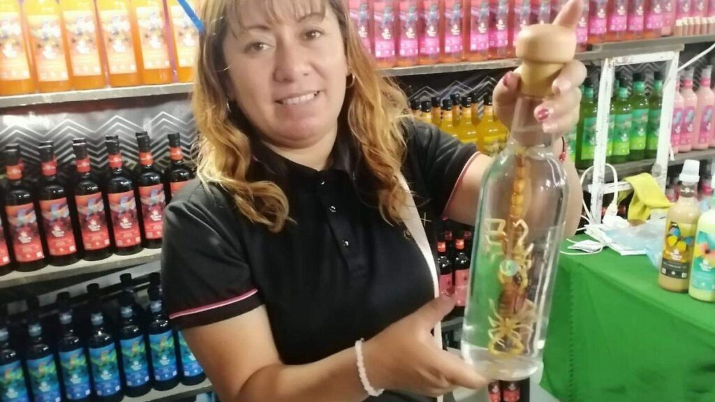 Exposición de productos oaxaqueños incluyendo botellas de mezcal artesanal, mole negro y chapulines en la Expo Nunthua en Villas del Salitre