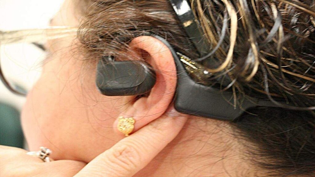 Joven usando audífonos a alto volumen, práctica que puede causar daños auditivos irreversibles como tinnitus y vértigo